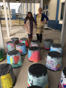 Volunteers with art programs collaborate with youth programs to decorate tree planters.