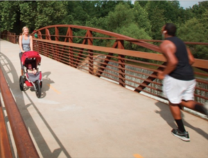 Joggers run across a greenway bridge in a sustainable south.