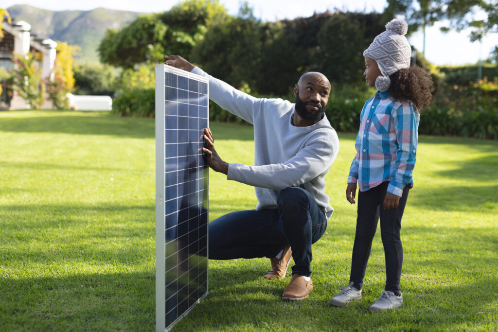 Image of happy african american father showing solar panels to d