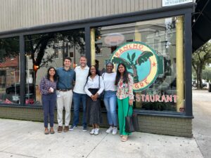 Six people stand in front of a restaurant window