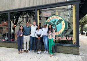 Six people stand in front of a restaurant window