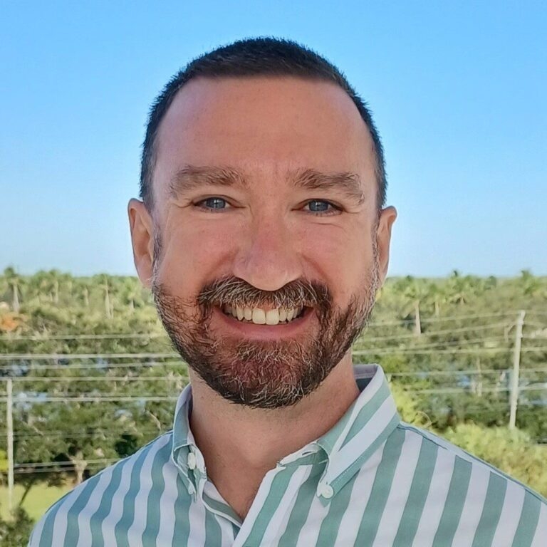 man smiling with trees in the background